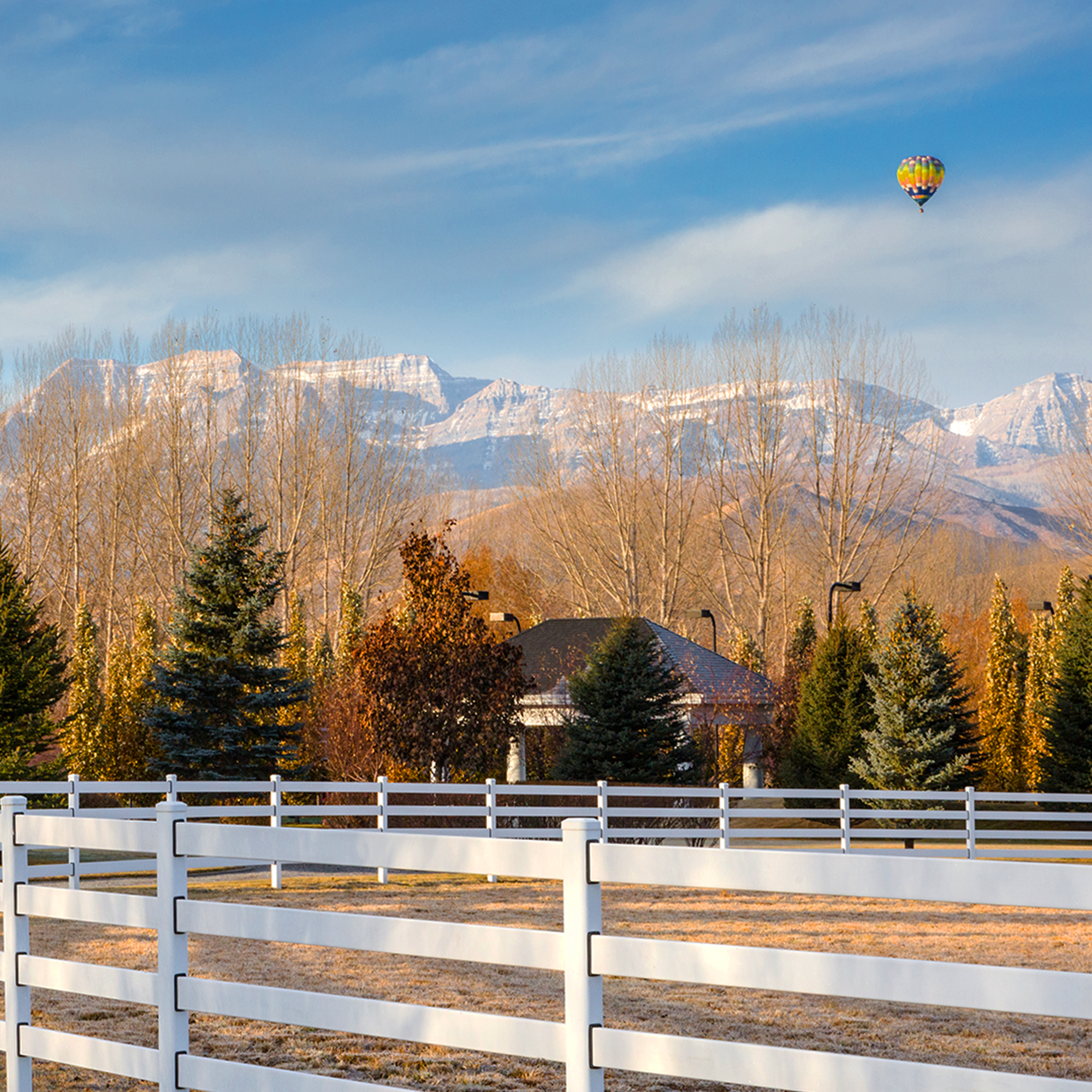 White ranch fence with mountains in the background